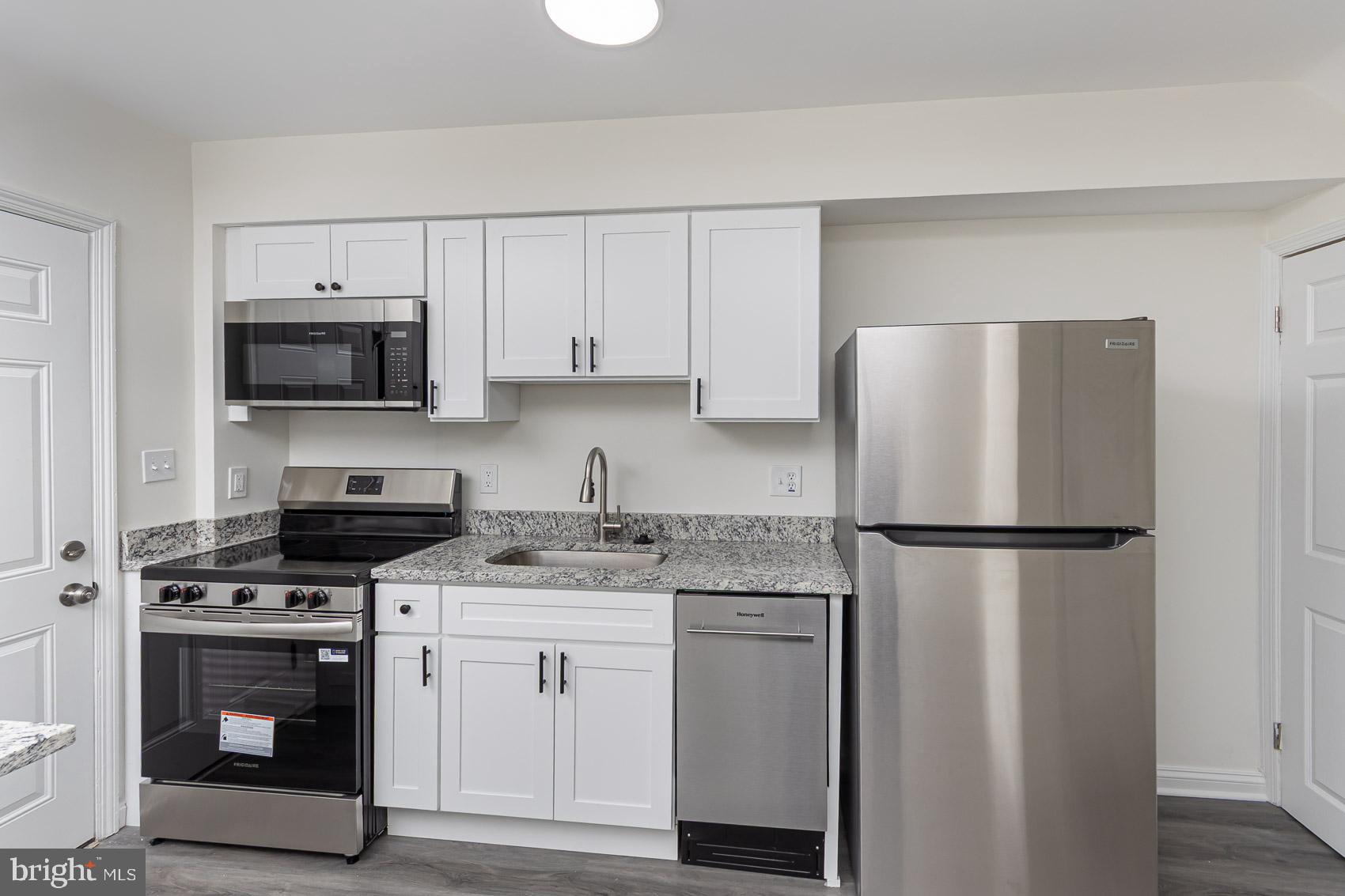 7035 Gough Street Baltimore, MD 21224 - Photo 4 of 25 a kitchen with cabinets stainless steel appliances and a wooden floor