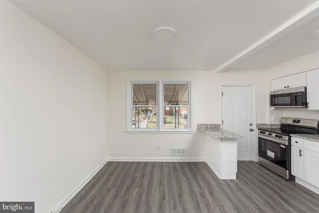 a kitchen with wooden floors and white cabinets