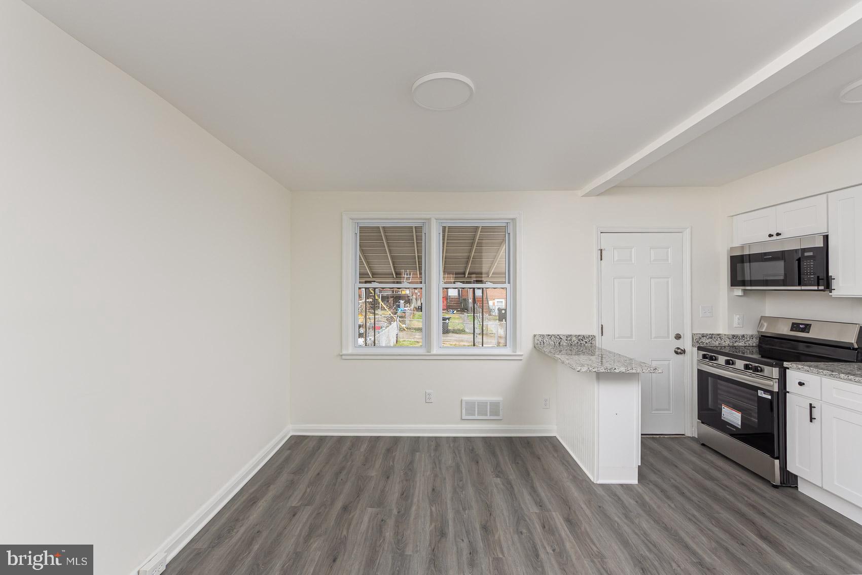 7035 Gough Street Baltimore, MD 21224 - Photo 6 of 25 a kitchen with wooden floors and white cabinets