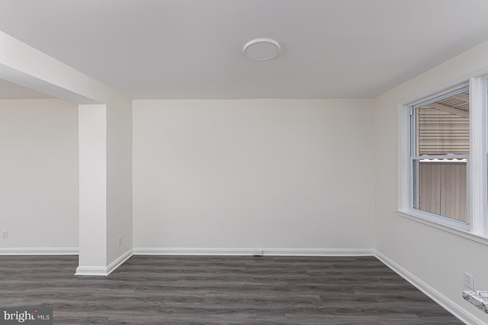7035 Gough Street Baltimore, MD 21224 - Photo 7 of 25 a view of an empty room with wooden floor and a window