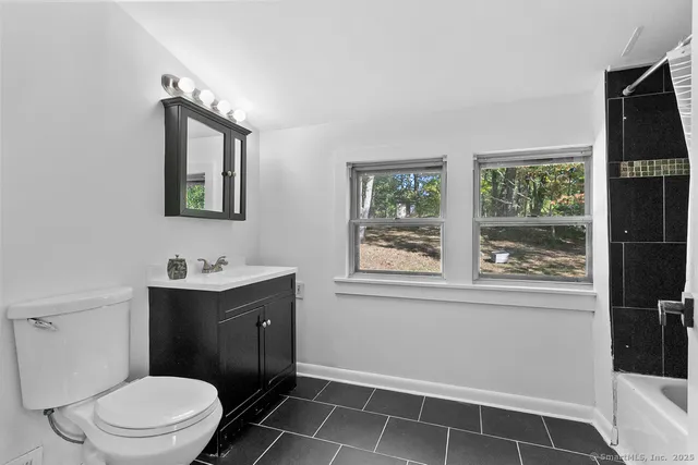 a bathroom with a toilet sink vanity and window