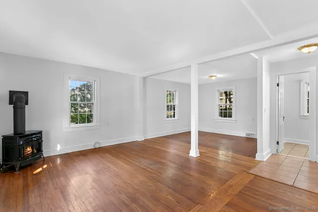 a view of an empty room with window and wooden floor
