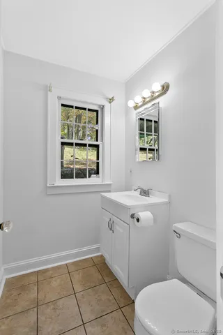 a bathroom with a toilet a sink a mirror and a window