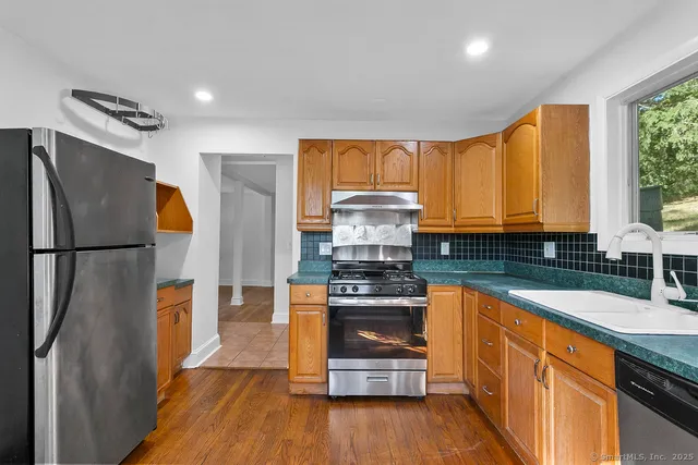 a kitchen with stainless steel appliances granite countertop a refrigerator a stove and a wooden floors