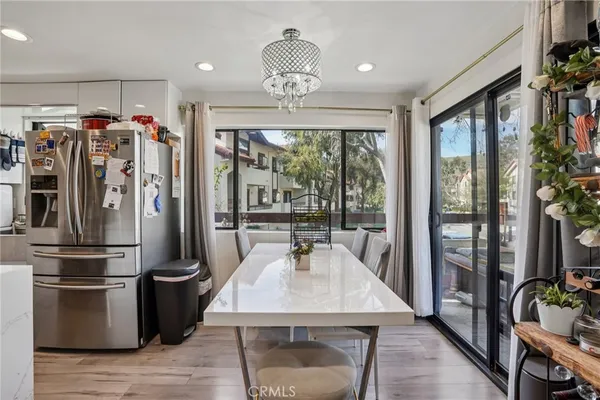 a kitchen with stainless steel appliances granite countertop a refrigerator a stove and a dining table with wooden floor