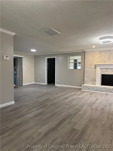 an empty room with wooden floor fireplace and windows