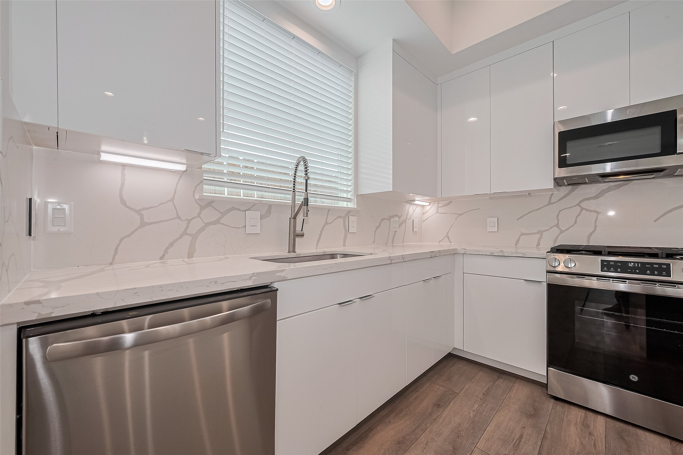 3510 Hadley Street Houston, TX 77004 - Photo 14 of 48 Crisp cabinetry and seamless quartz surfaces are paired with a complementing backsplash, while under-cabinet lighting casts a gentle glow across the counters—combining form and function beautifully in the kitchen.