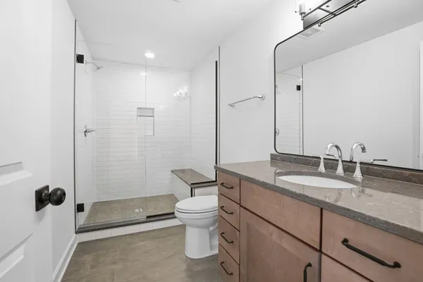 a bathroom with a granite countertop sink a toilet and shower