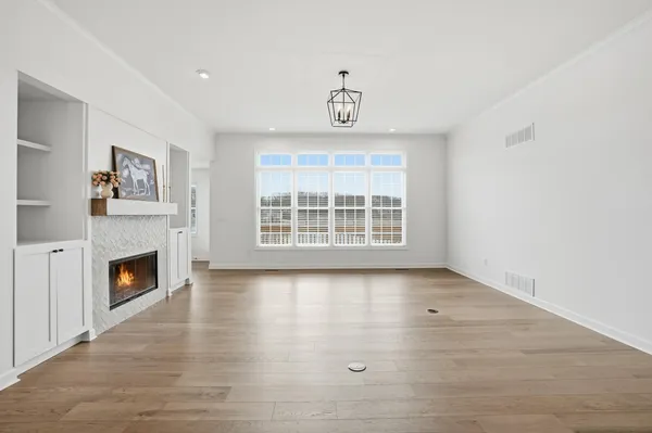 an empty room with windows fireplace and cabinet