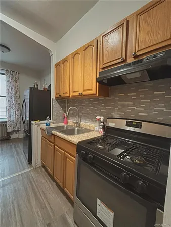 a kitchen with granite countertop a stove top oven a sink dishwasher and cabinets with wooden floor