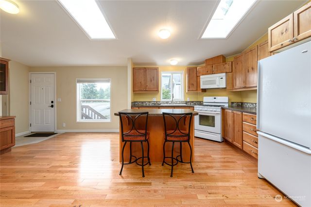 a kitchen with stainless steel appliances kitchen island granite countertop wooden floors and white cabinets
