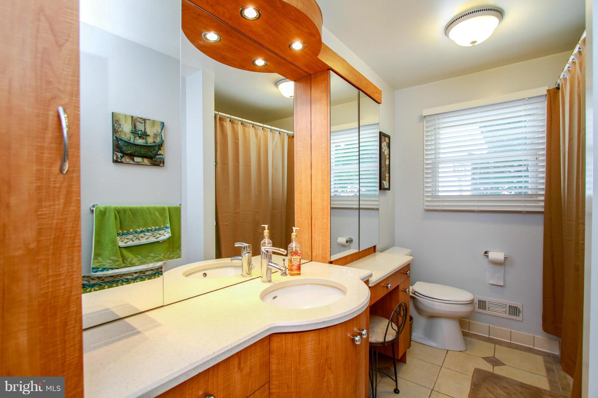 6202 Collinsway Road Baltimore, MD 21228 - Photo 16 of 30 a bathroom with a double vanity sink toilet and mirror