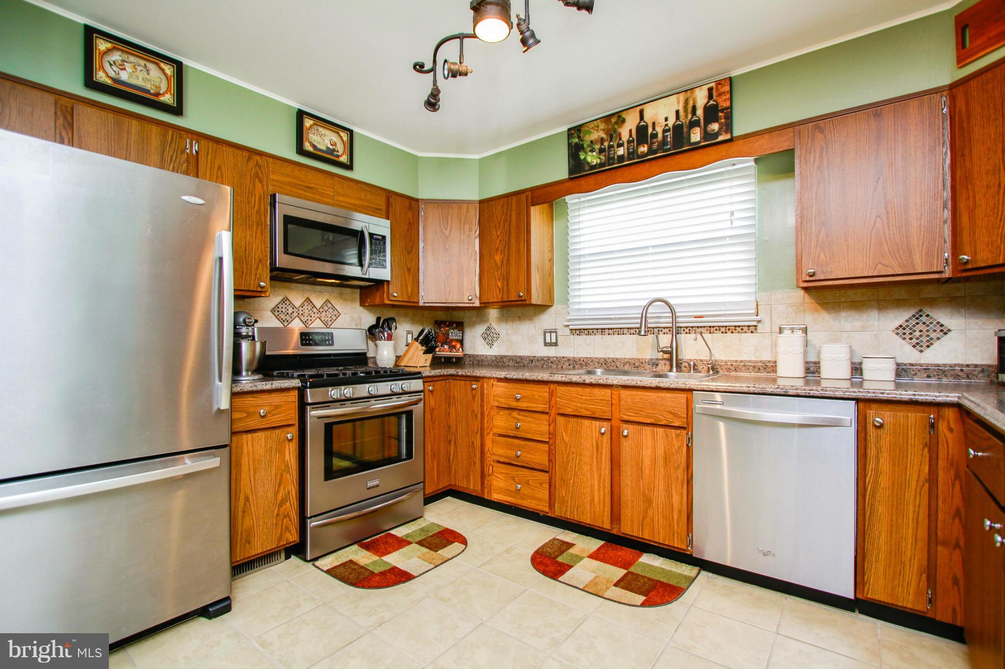 6202 Collinsway Road Baltimore, MD 21228 - Photo 7 of 30 a kitchen with stainless steel appliances granite countertop a sink a stove a refrigerator cabinets and a window