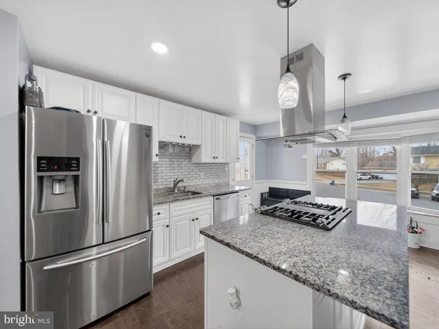 a kitchen with stainless steel appliances granite countertop a refrigerator a stove and a sink