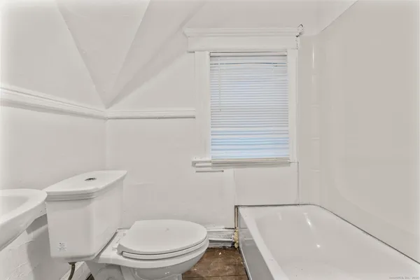 a white toilet sitting next to a bath tub