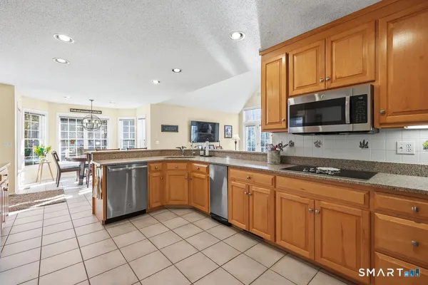 a large kitchen with stainless steel appliances granite countertop a stove top oven a sink dishwasher a dining table and chairs with wooden floor