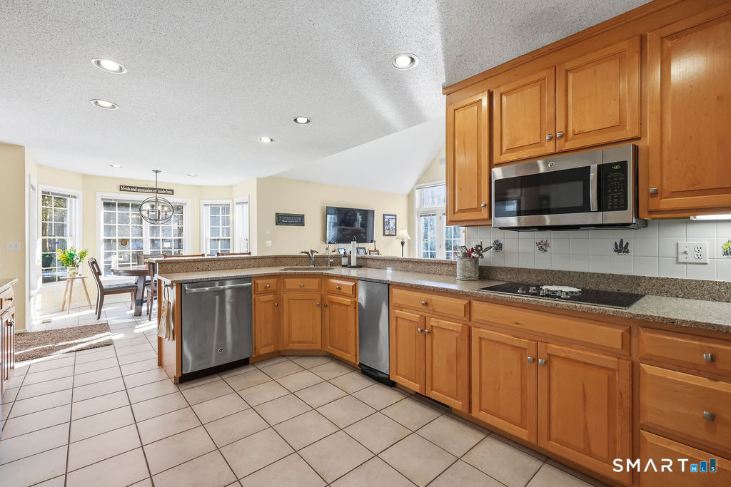 73 High Valley Drive Canton, CT 06019 - Photo 21 of 37 a large kitchen with stainless steel appliances granite countertop a stove top oven a sink dishwasher a dining table and chairs with wooden floor