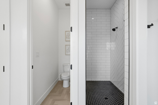 2278 Tawny Ridge Circle St. George, UT 84790 - Photo 28 of 61 Contemporary shower stall featuring white subway tile in a herringbone pattern, a black hexagonal tile floor, and a matte black shower head.