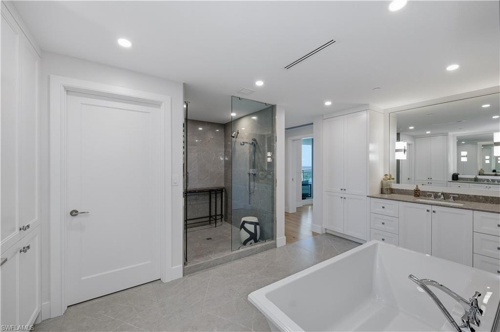 13925 Old Coast Road, Unit 1706 Naples, FL 34110 - Photo 16 of 37 a large bathroom with a large mirror vanity and shower