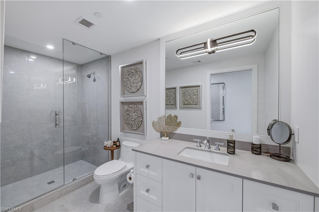 13925 Old Coast Road, Unit 1706 Naples, FL 34110 - Photo 23 of 37 a bathroom with a granite countertop sink toilet mirror and shower