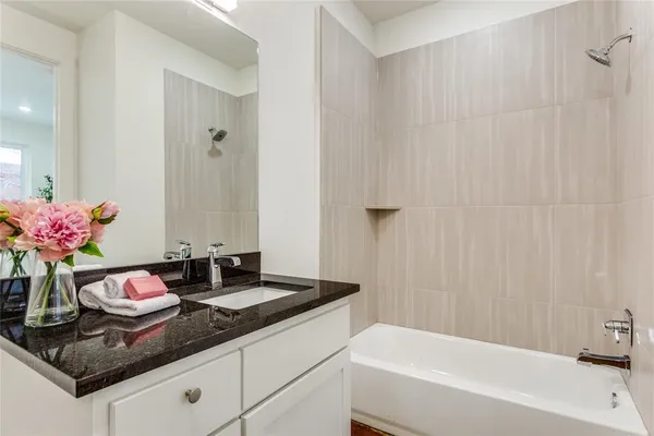 a bathroom with a granite countertop sink and a bathtub