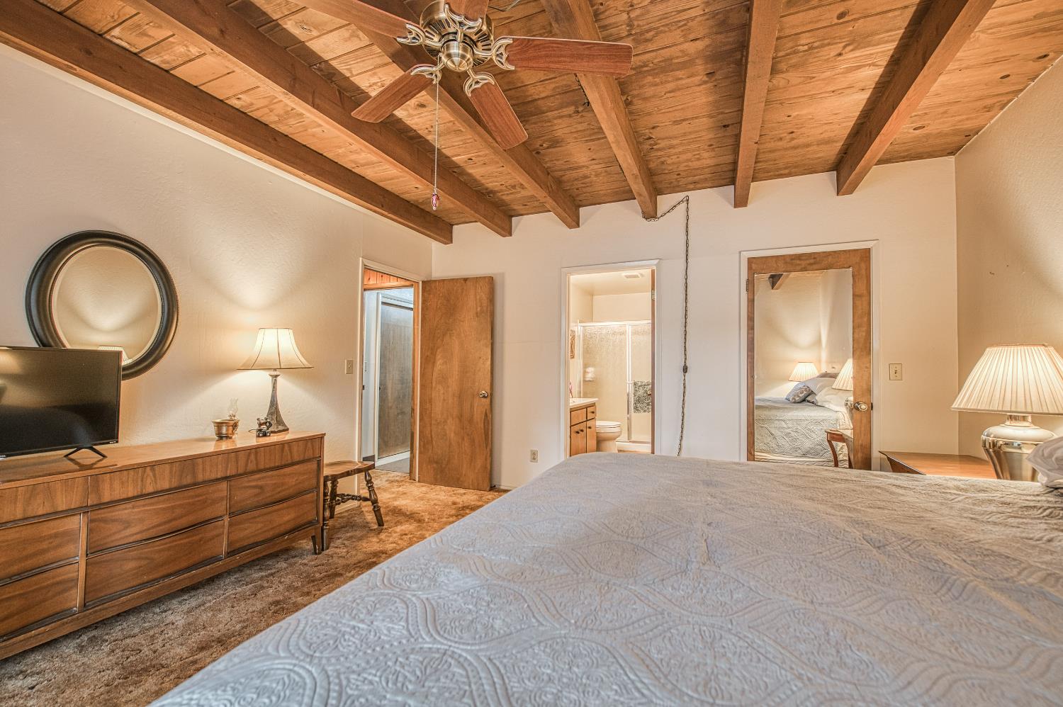 42303 Hanging Branch Road Shaver Lake, CA 93664 - Photo 22 of 39 a bedroom with a bed a mirror on dresser and a chandelier