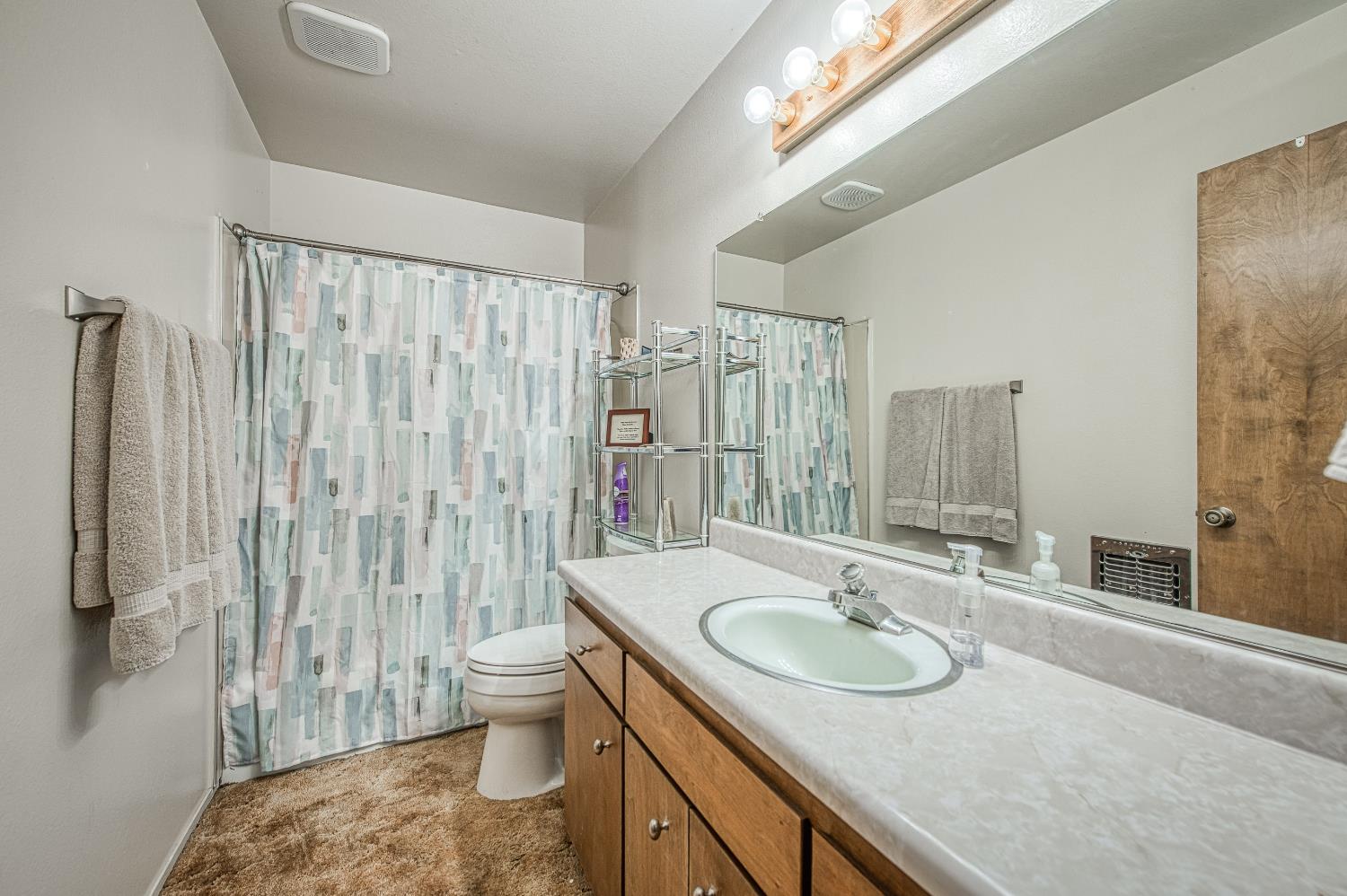 42303 Hanging Branch Road Shaver Lake, CA 93664 - Photo 32 of 39 a bathroom with a sink toilet a mirror and shower curtain