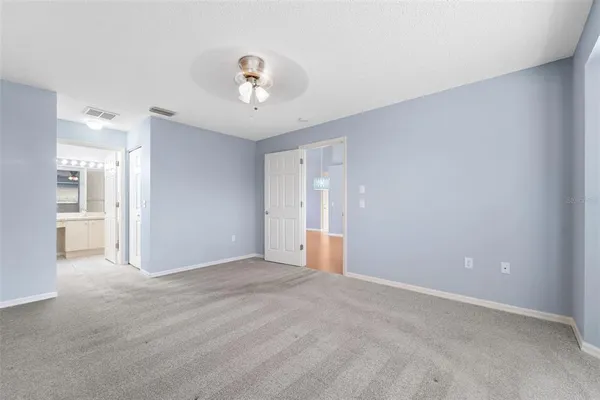 a view of an empty room with wooden floor and a kitchen