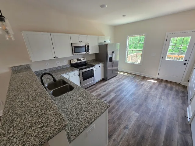 a kitchen with stainless steel appliances granite countertop a stove a sink dishwasher and a microwave oven with wooden floor