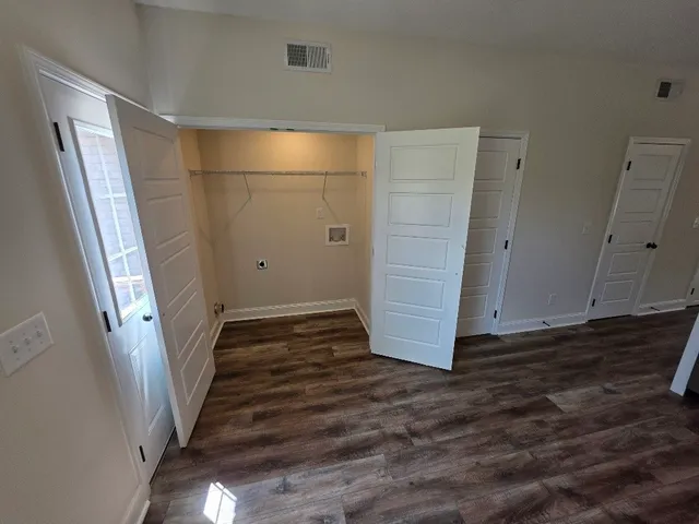 a view of a hallway with wooden floor and cabinet