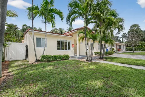 a view of a house with a yard and palm trees
