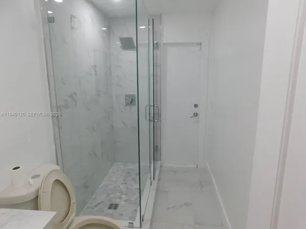 a bathroom with a granite countertop bathtub shower and toilet