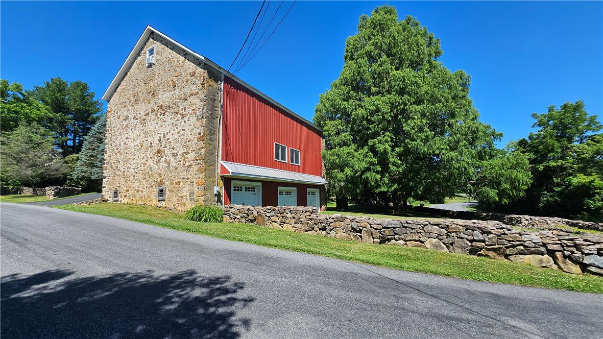 585 Buttermilk Road Hellertown, PA 18055 - Photo 65 of 82 A striking stone and red-sided barn stands beside a winding asphalt driveway.