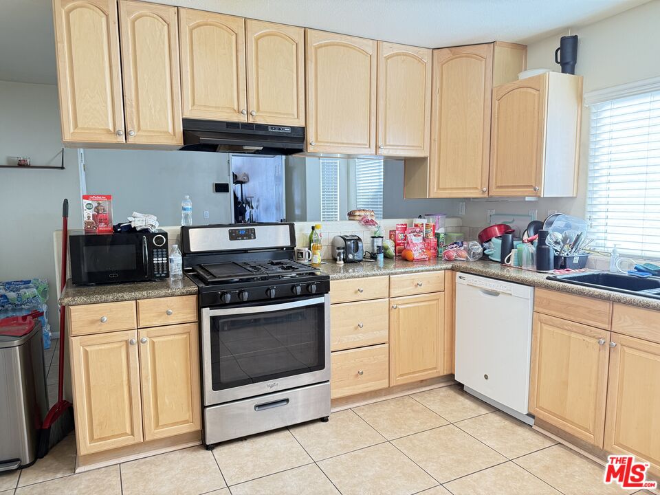 18238 Kalin Ranch Drive Victorville, CA 92395 - Photo 15 of 33 a kitchen with stainless steel appliances granite countertop a stove a sink and white cabinets