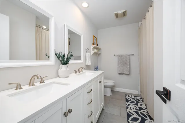 a bathroom with a double vanity sink mirror and toilet