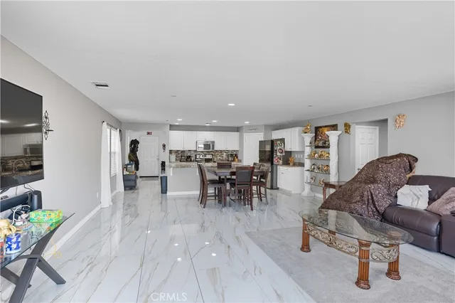 a living room with stainless steel appliances kitchen island granite countertop a refrigerator a stove and a sink with wooden floor