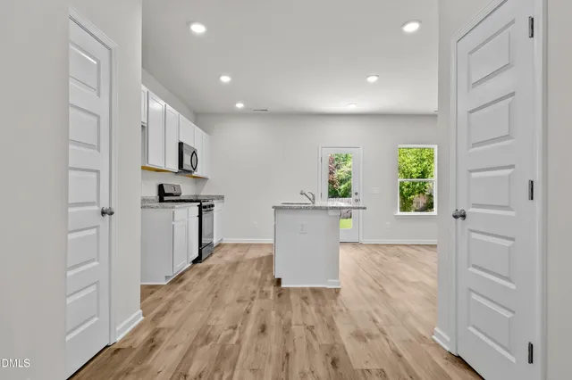 a view of kitchen with microwave a refrigerator and wooden floor