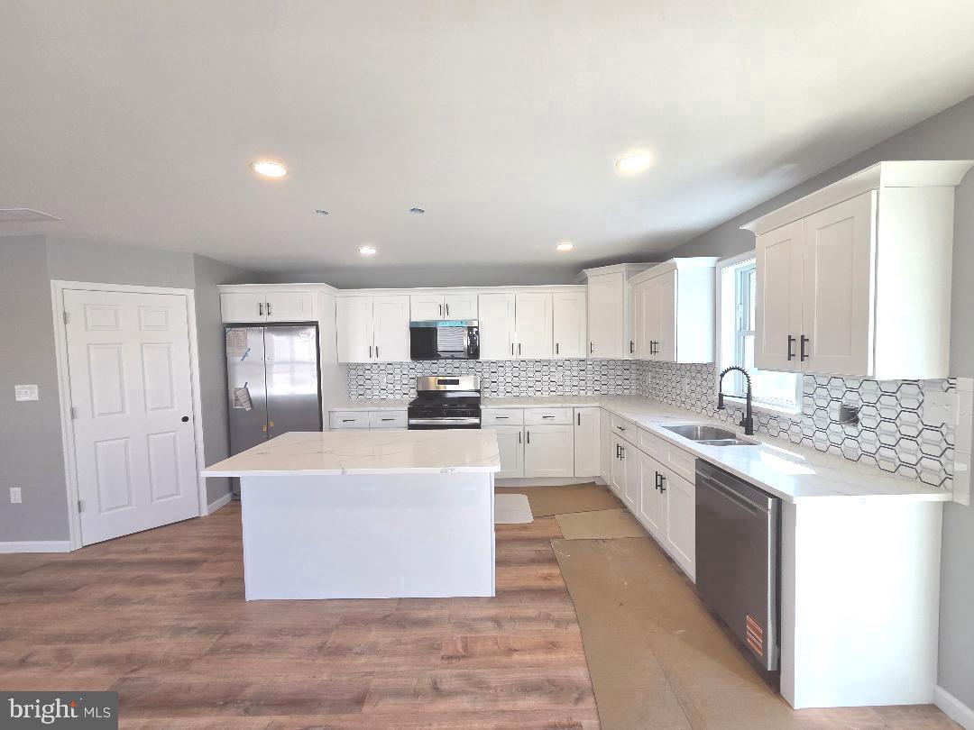 730 Excelsior Avenue Croydon, PA 19021 - Photo 2 of 10 a large white kitchen with kitchen island a sink a stove a refrigerator and white cabinets