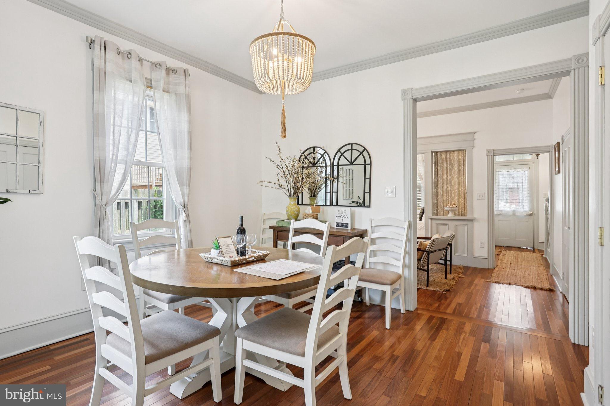 416 Broadway Cape May, NJ 08204 - Photo 31 of 49 a dining room with wooden floor a chandelier a wooden table and chairs