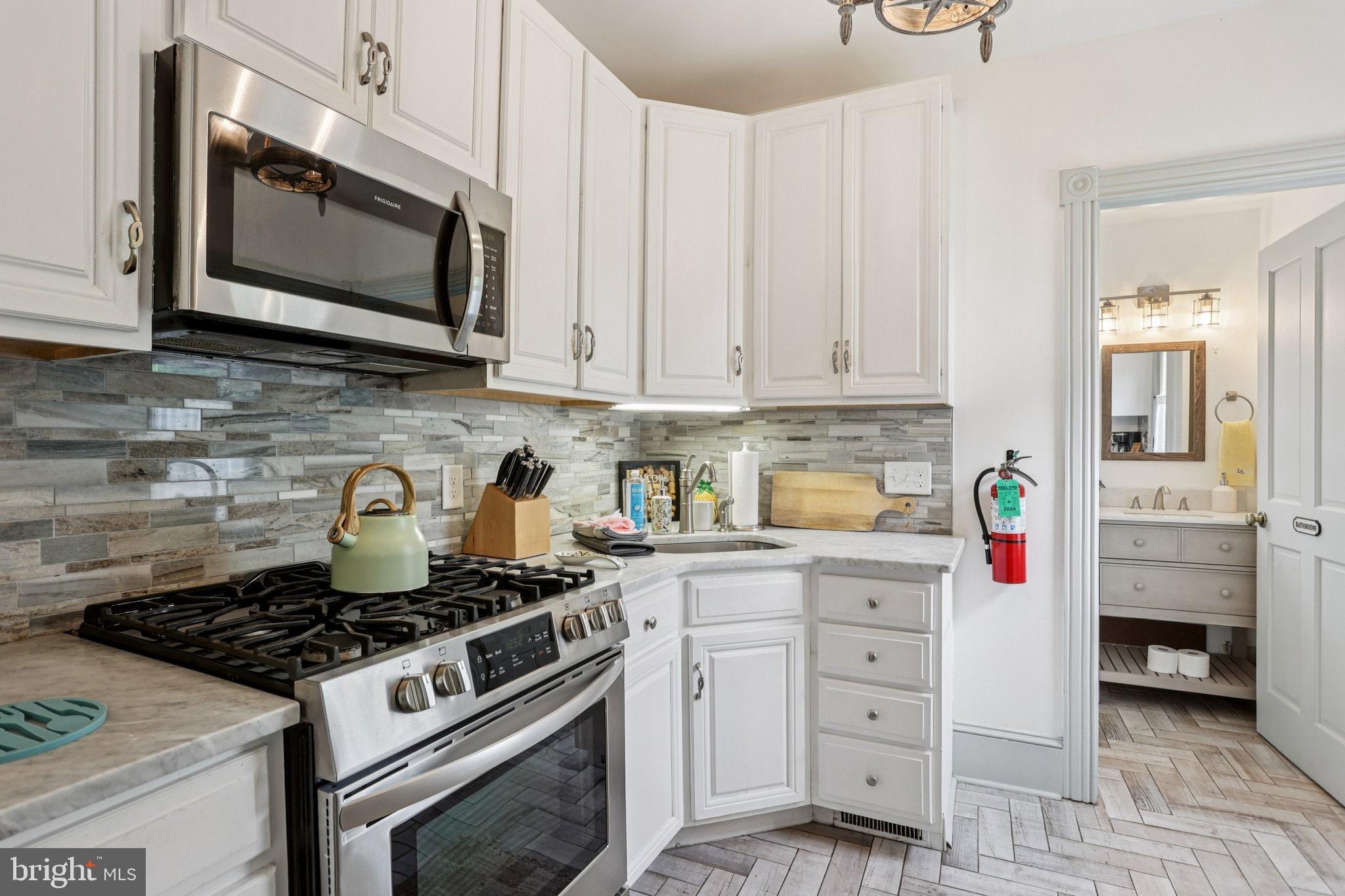 416 Broadway Cape May, NJ 08204 - Photo 35 of 49 a kitchen with stainless steel appliances a stove a microwave and cabinets