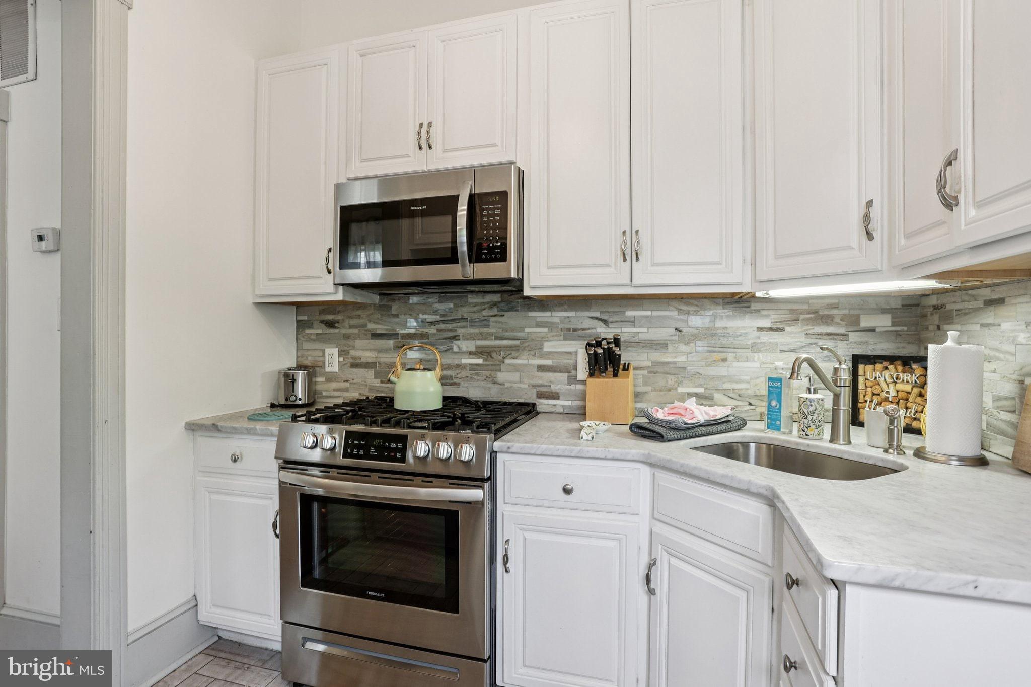416 Broadway Cape May, NJ 08204 - Photo 37 of 49 a kitchen with stainless steel appliances granite countertop white cabinets a stove a sink and dishwasher
