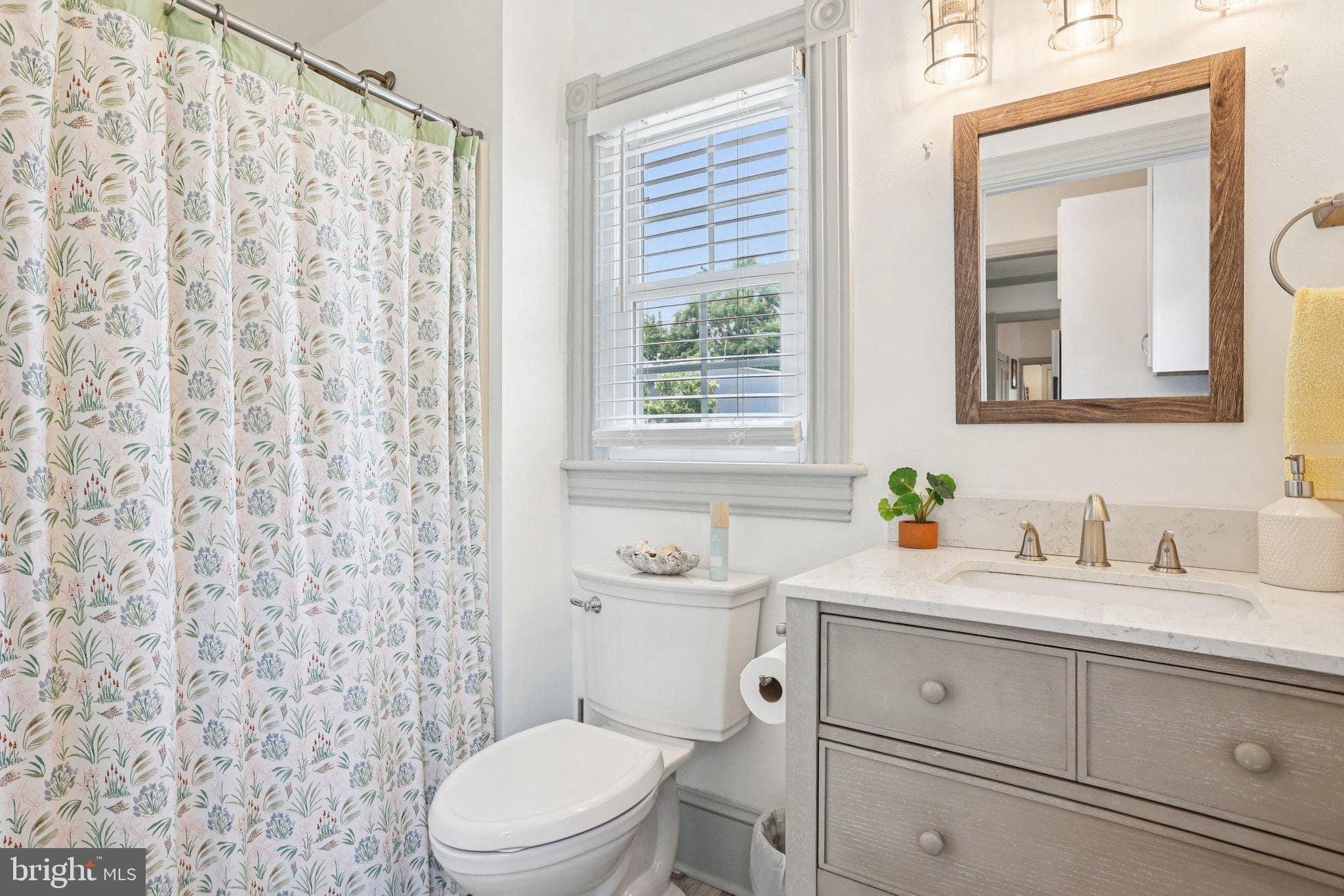 416 Broadway Cape May, NJ 08204 - Photo 38 of 49 a bathroom with a granite countertop toilet a sink a mirror and a shower