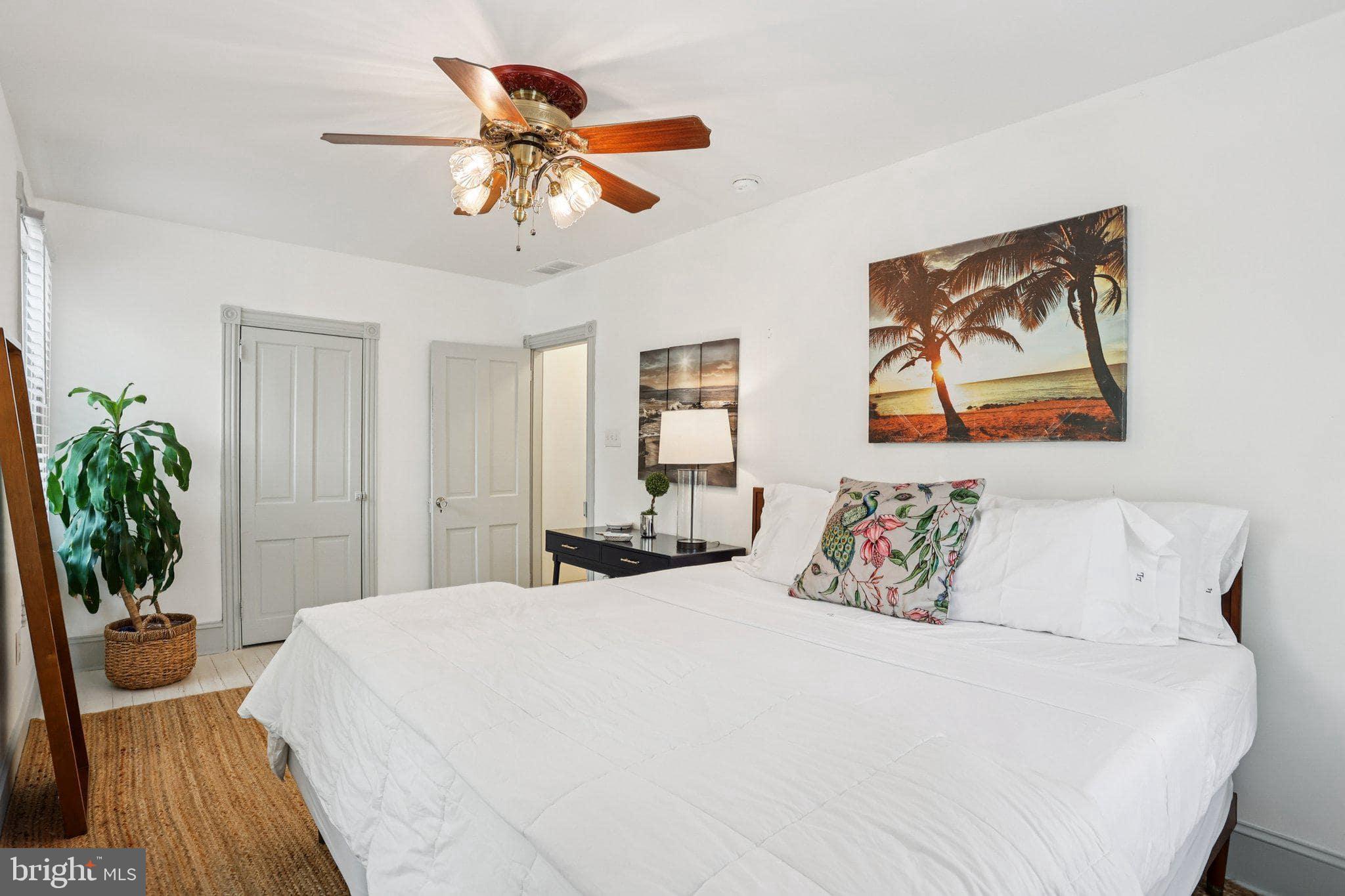 416 Broadway Cape May, NJ 08204 - Photo 43 of 49 a bedroom with a large bed a chandelier and a painting on the wall