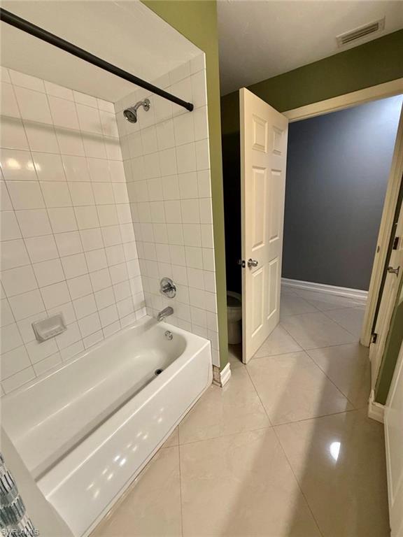 3908 Lee Boulevard Lehigh Acres, FL 33971 - Photo 11 of 24 Bathroom with tiled shower / bath combo, tile patterned floors, and toilet