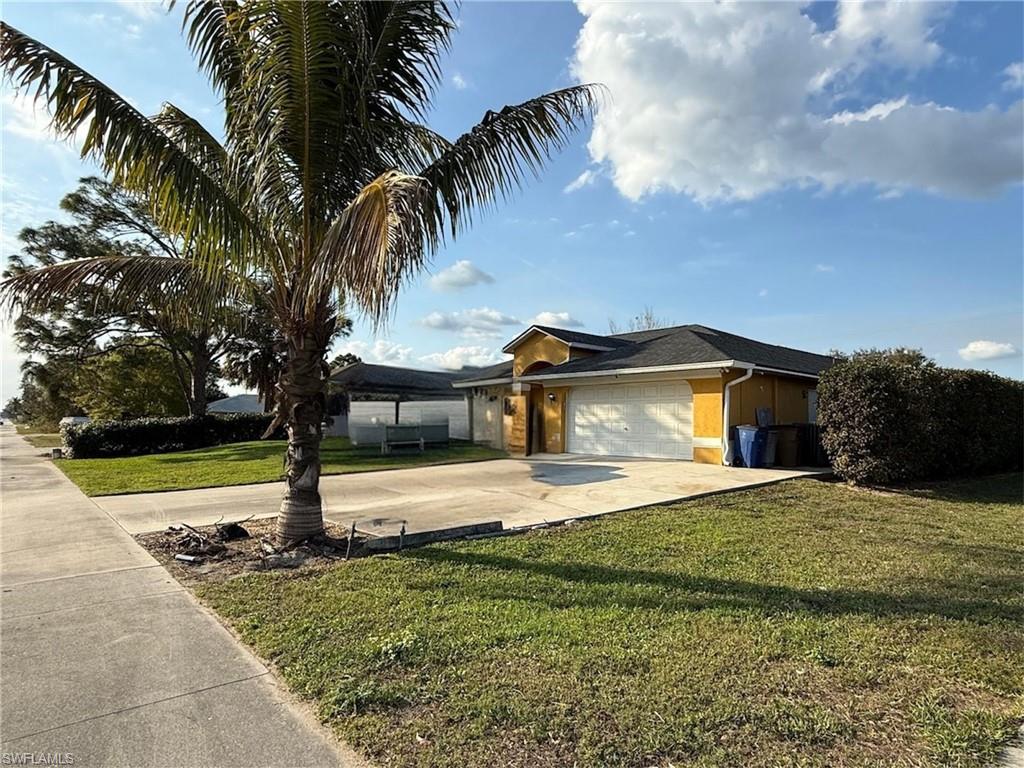 3908 Lee Boulevard Lehigh Acres, FL 33971 - Photo 2 of 24 View of front of home featuring a garage and a front lawn