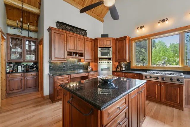 a kitchen with stainless steel appliances granite countertop a sink a stove and a wooden floors