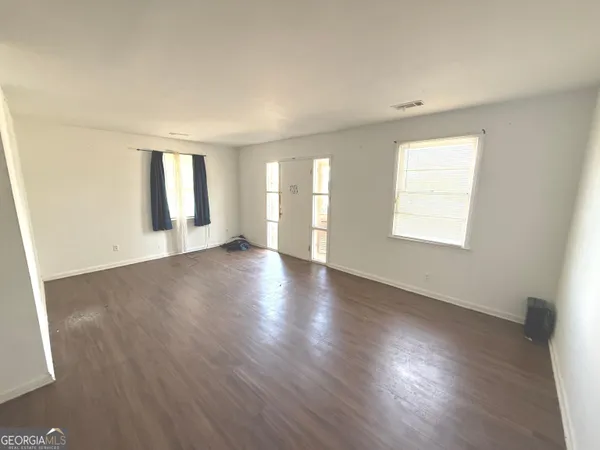an empty room with wooden floor and windows