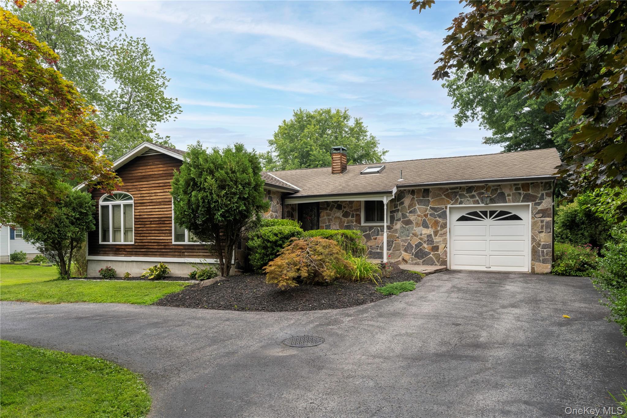 a front view of a house with a garden and trees
