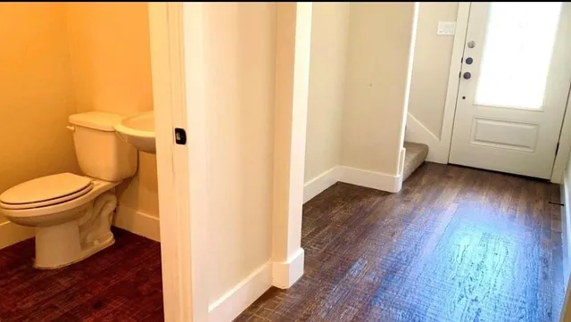 a bathroom with a toilet and a hardwood floor