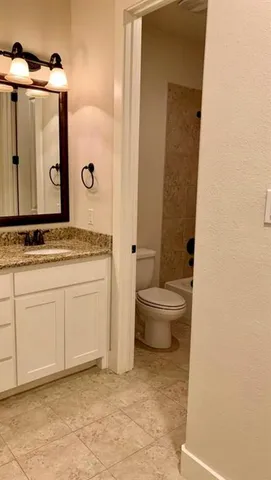 a bathroom with a granite countertop sink and a toilet